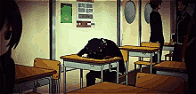 Un jeune lycéen en uniforme noir est assis seul à son pupitre dans une salle de classe. Il a la tête enfouie dans ses bras posés sur la table, dans une posture de profond abattement. À l'arrière-plan, d'autres élèves discutent près de la porte, créant un contraste entre leur interaction sociale et l'isolement du personnage au premier plan.